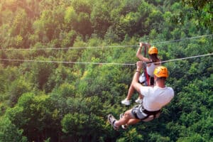 couple ziplining through the mountains at sunset