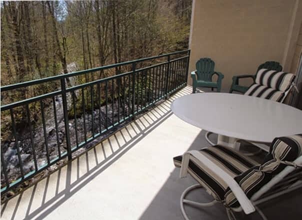 A Gatlinburg condo’s private balcony with patio furniture overlooking a river.