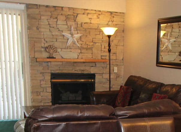 A mountain stone fireplace in a Gatlinburg condo surrounded by furniture.