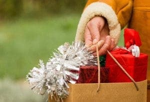 A woman holding a bag full of Christmas gifts.