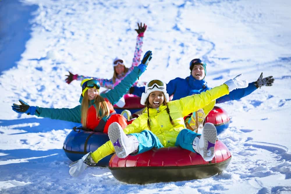 friends snow tubing down a hill