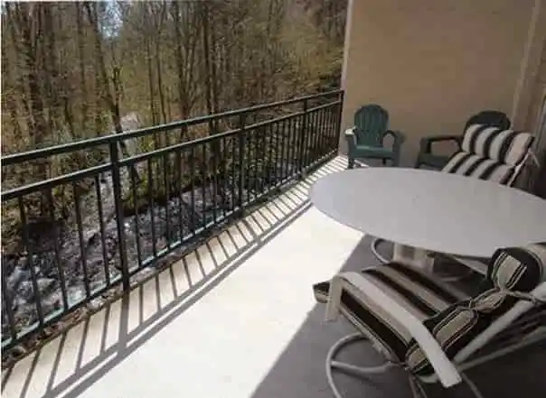 A Gatlinburg condo’s private balcony with patio furniture overlooking a river.